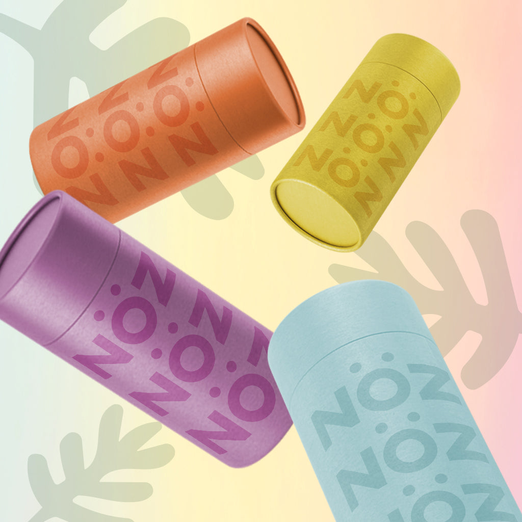 Four floating bottles of Nöz’s reef-safe sunscreen in the colors orange, yellow, purple, and blue